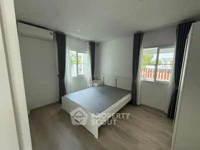 Spacious bedroom with large windows and modern minimalist design, featuring a comfortable bed and air conditioning.