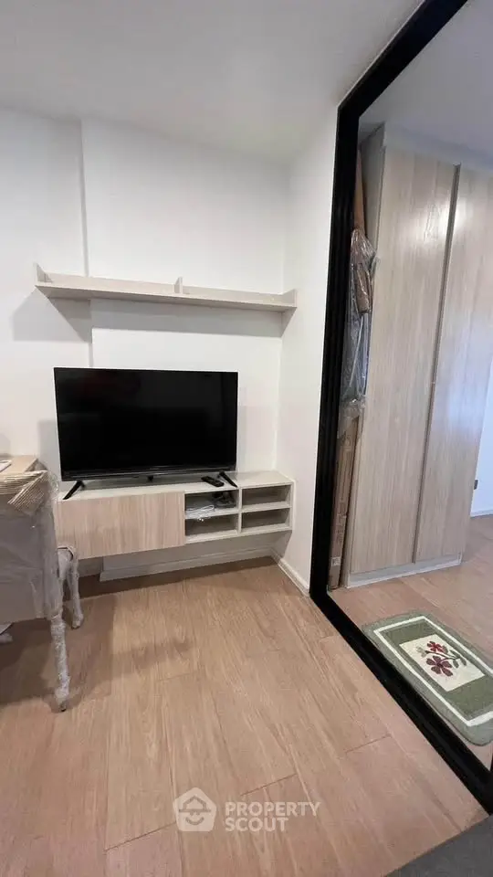 Modern living room with sleek TV stand and mirrored wardrobe in cozy apartment.