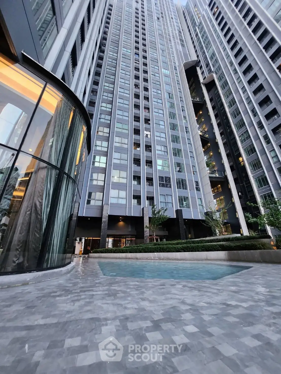 Modern high-rise building with sleek architecture and outdoor pool area, perfect for urban living.