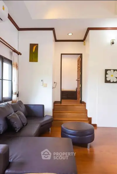 Charming living room with cozy leather sofa and wooden flooring, perfect for relaxation and comfort.