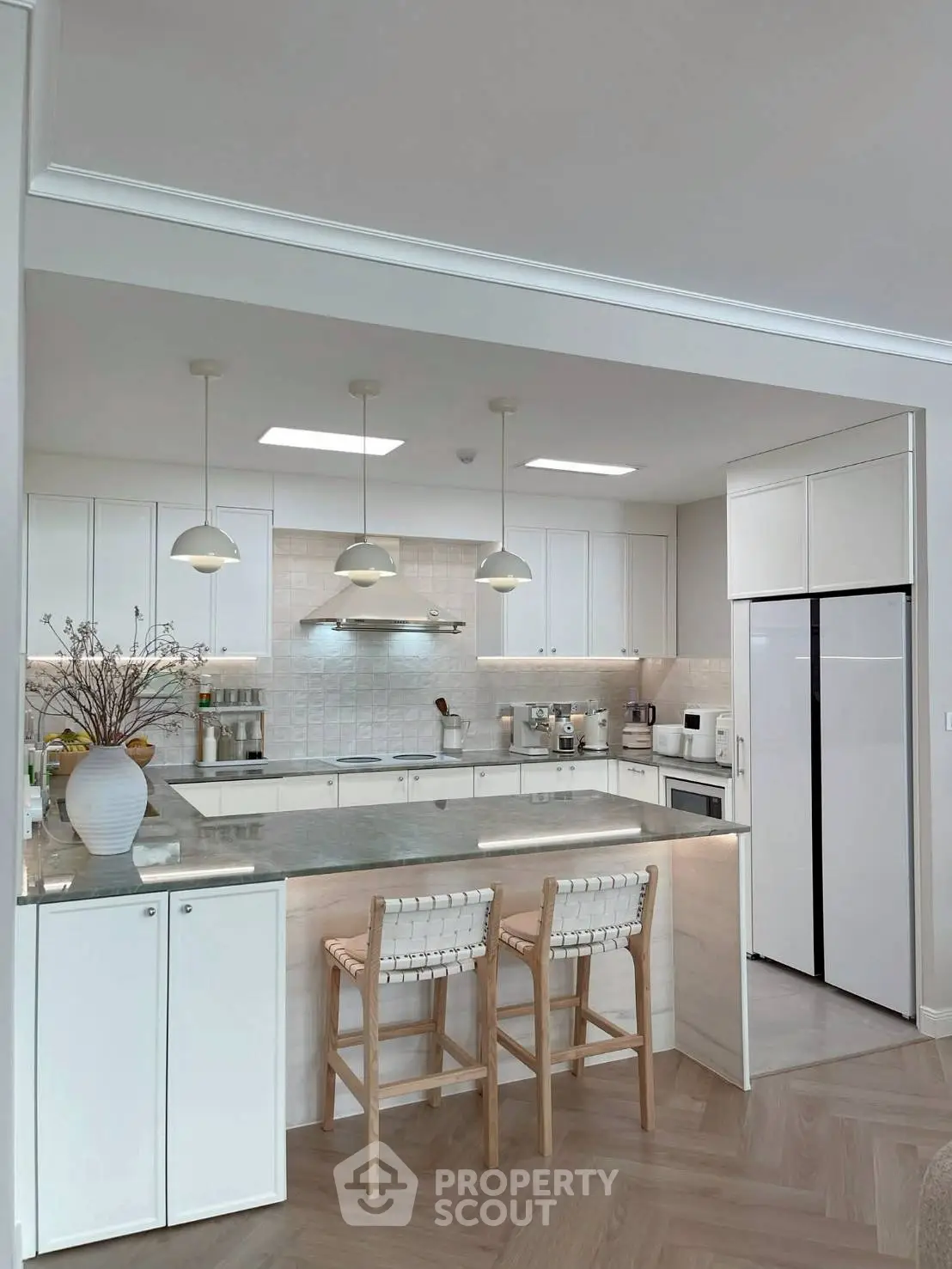 Modern kitchen with sleek white cabinets, island seating, and stainless steel appliances.