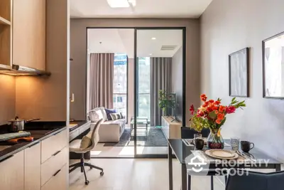 Modern open-plan kitchen with sleek countertops flows into a cozy living space, leading to a sunlit balcony, perfect for urban living.