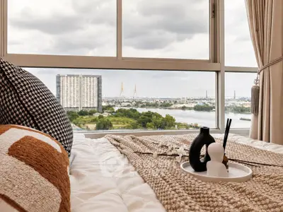 Luxurious bedroom with stunning river and city view from large window.