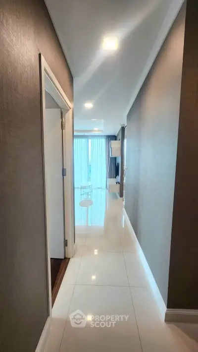 Elegant hallway leading to a bright living room with modern decor and large windows.