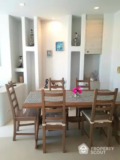 Charming dining area with wooden table and chairs, accented by built-in shelves and decorative items.