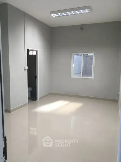 Minimalist empty room with tiled floor and small window, ideal for customization.