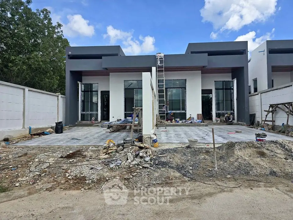 Modern townhouse under construction with sleek design and spacious driveway