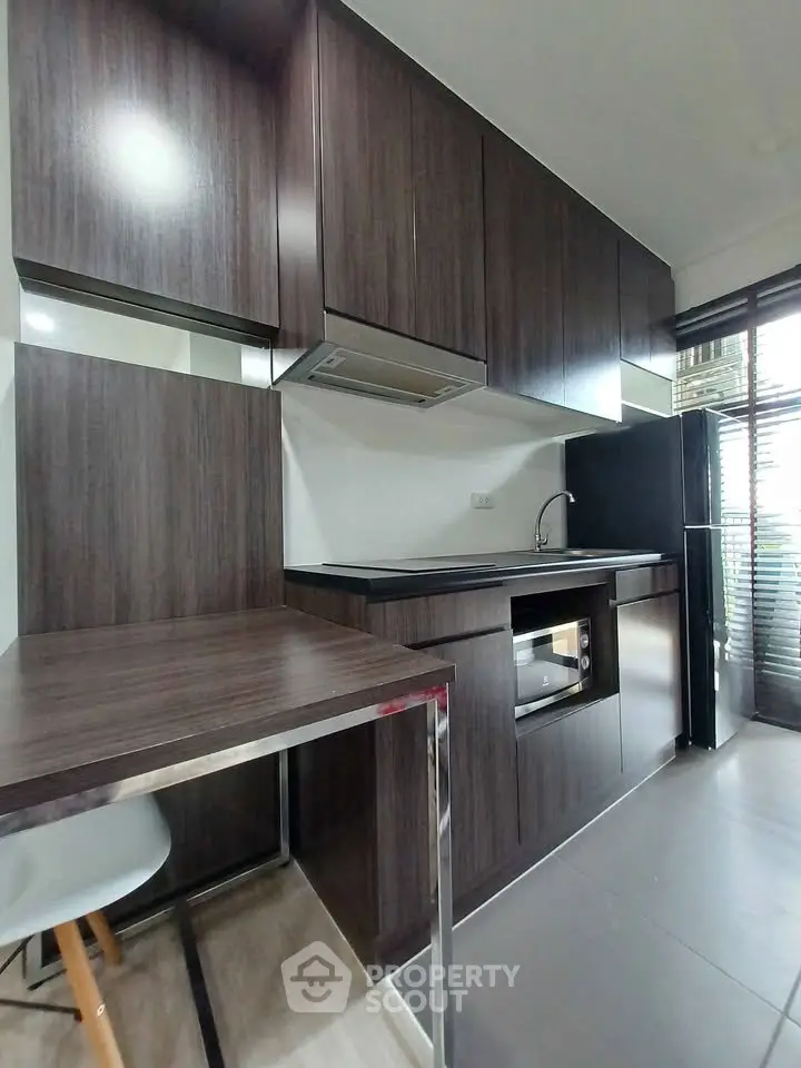 Modern kitchen with sleek dark wood cabinets and built-in appliances in a contemporary apartment.