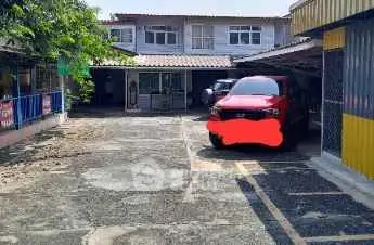 Spacious parking area in front of residential building with red car parked.