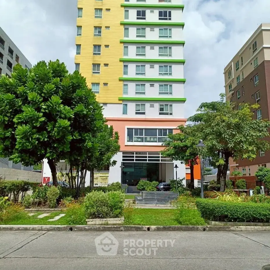 Modern multi-story residential building with vibrant facade and lush greenery