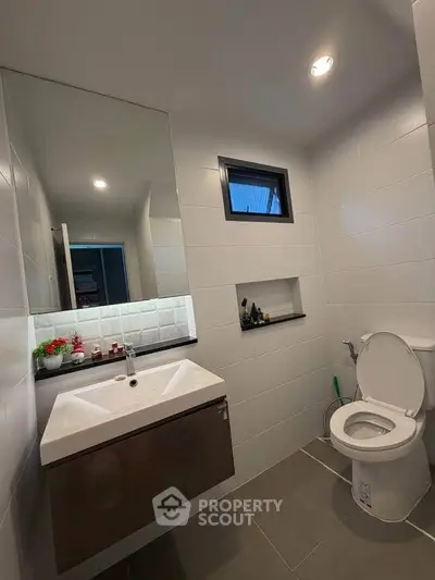 Modern bathroom with sleek fixtures and contemporary design, featuring a wall-mounted sink and stylish lighting.