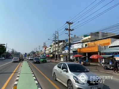 Bustling street view with shops and cars, showcasing vibrant urban life.