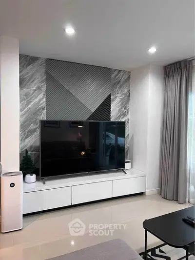 Modern living room with sleek TV setup and stylish geometric wall design.