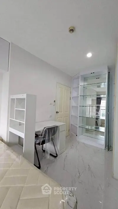 Modern bedroom with sleek white furniture and built-in shelving, ideal for urban living.