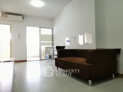Modern living room with brown sofa and glass door leading to balcony, featuring minimalist decor.