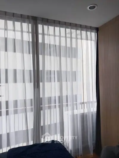 Modern bedroom with floor-to-ceiling windows and sheer curtains