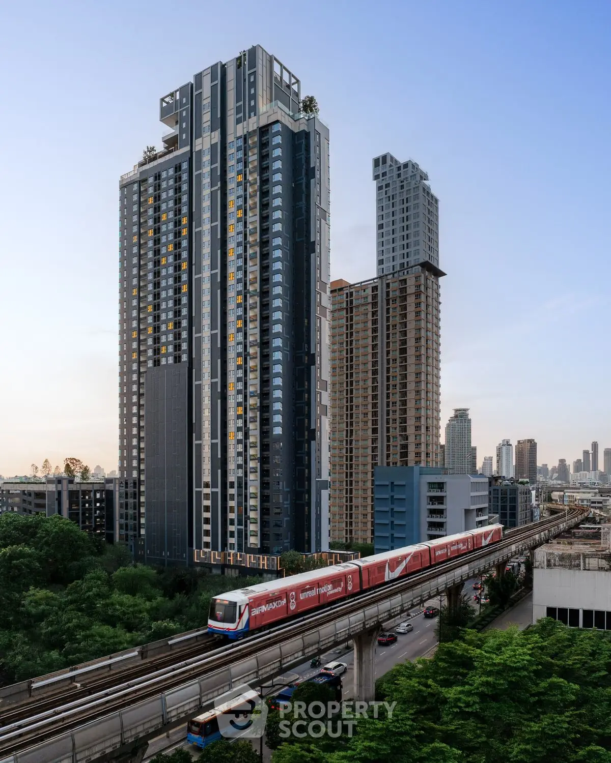 Modern high-rise buildings with train and lush greenery in urban setting.