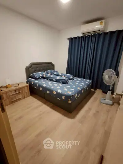 Cozy bedroom with modern decor, featuring a comfortable bed, stylish nightstand, and air conditioning.