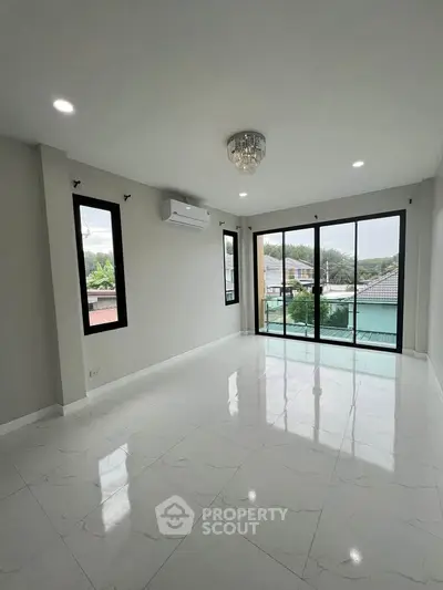 Spacious living room with large windows and balcony offering natural light and scenic views.