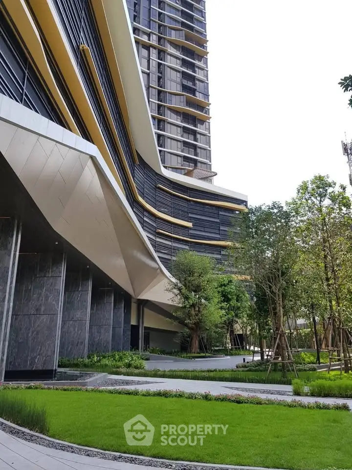 Modern high-rise building with lush landscaped garden and sleek architectural design.