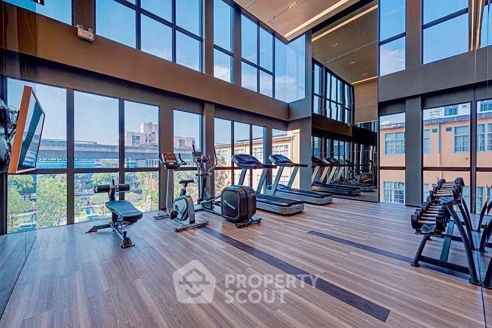 Modern gym with large windows and fitness equipment in luxury building.