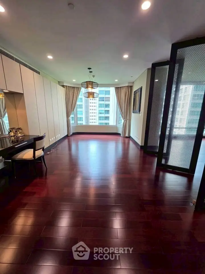 Spacious living room with elegant hardwood floors and large windows offering city views.