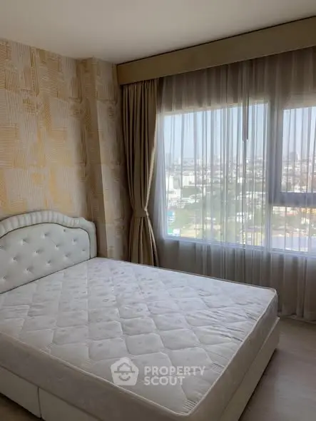 Bright bedroom with large window and city view, featuring elegant curtains and a comfortable bed.