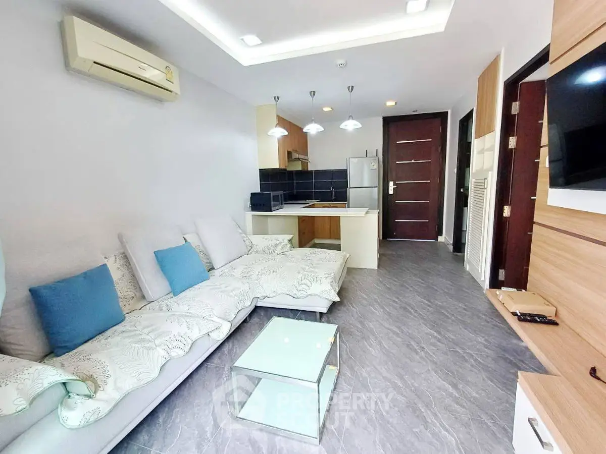 Modern living room with sleek design and open kitchen layout, featuring stylish lighting and cozy seating.