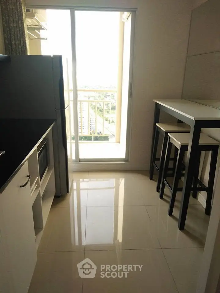 Modern kitchen with sleek design and balcony view, featuring high table and chairs.