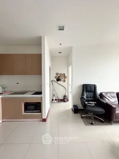 Modern apartment interior with sleek kitchen and cozy living area featuring leather seating and stylish decor.