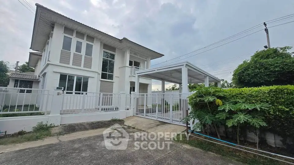Modern two-story house with gated driveway and lush greenery, perfect for family living.