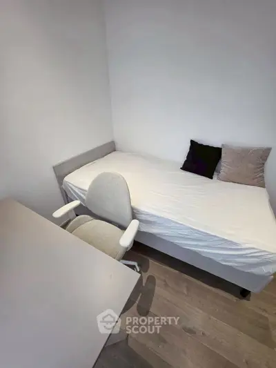 Cozy minimalist bedroom with single bed and desk, perfect for a student or professional.