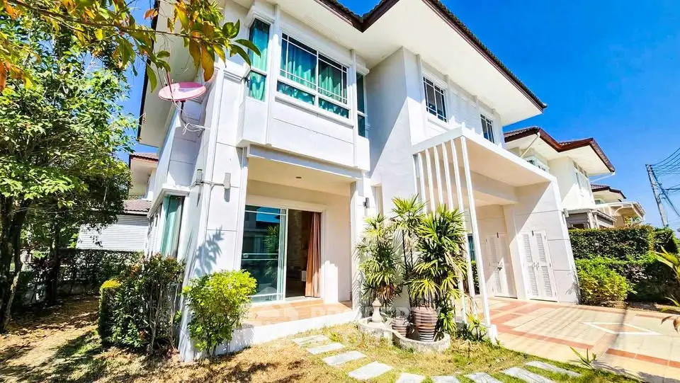 Charming two-story house with lush garden and modern facade under clear blue sky.