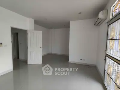 Spacious unfurnished room with large window and air conditioning, perfect for customization.