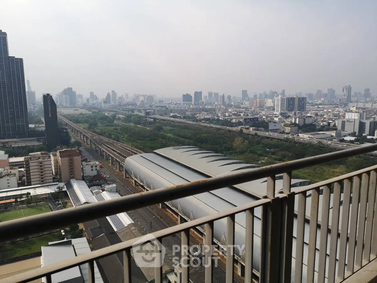 Stunning cityscape view from high-rise balcony overlooking urban skyline and railway tracks.