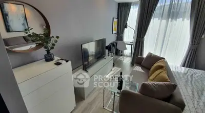 Modern living room with stylish decor, large TV, and natural light from floor-to-ceiling windows.