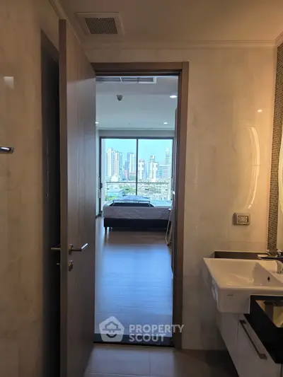 Modern apartment with city view from bedroom, featuring sleek bathroom design.