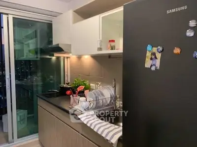 Modern kitchen with sleek black appliances and open layout, featuring a Samsung fridge and stylish decor.