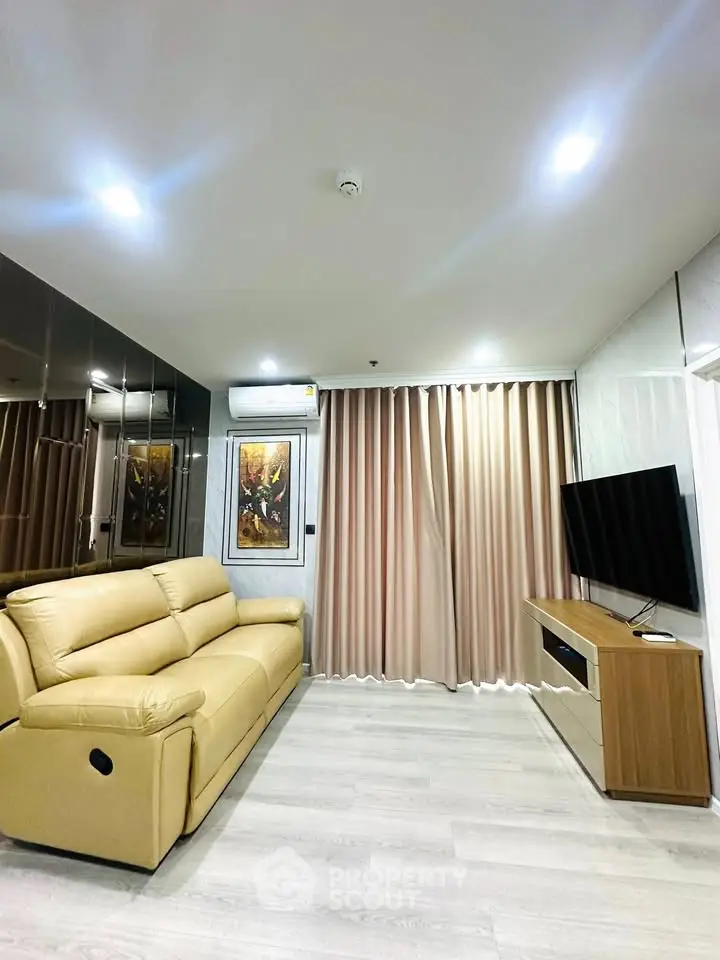 Modern living room with beige sofa, wall-mounted TV, and elegant curtains in a stylish apartment.