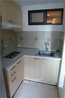 Compact kitchen with modern cabinetry and tiled backsplash in cozy apartment