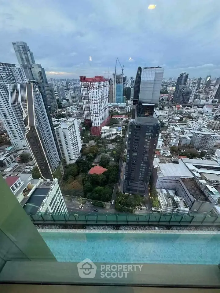 Stunning cityscape view from high-rise building with pool overlooking urban skyline.