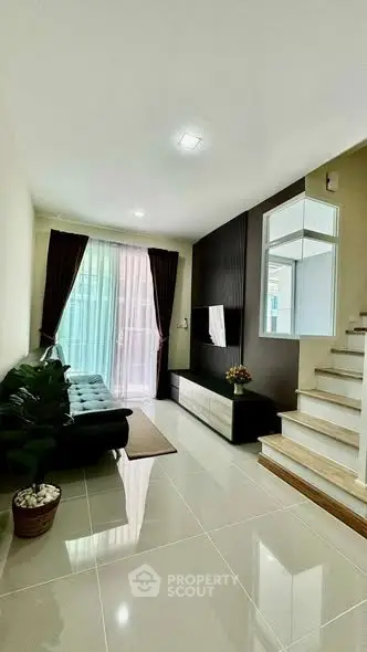 Modern living room with sleek staircase and natural light, perfect for stylish urban living.