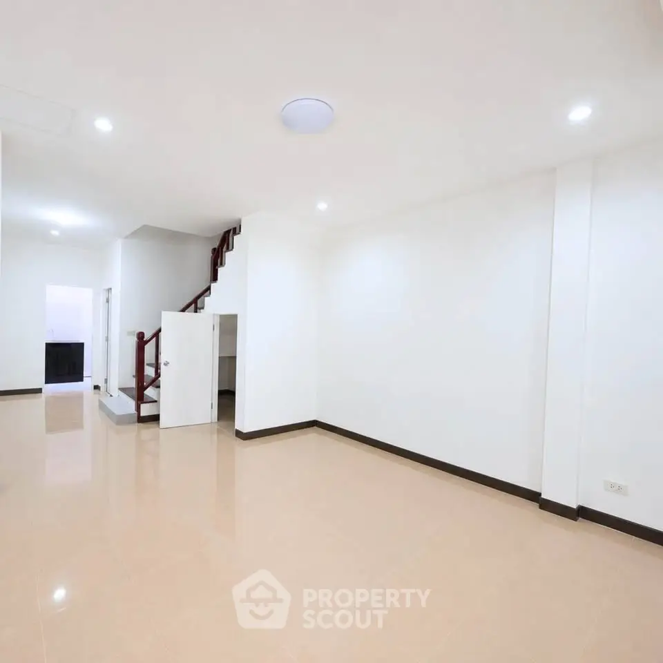 Spacious empty living room with staircase and modern lighting