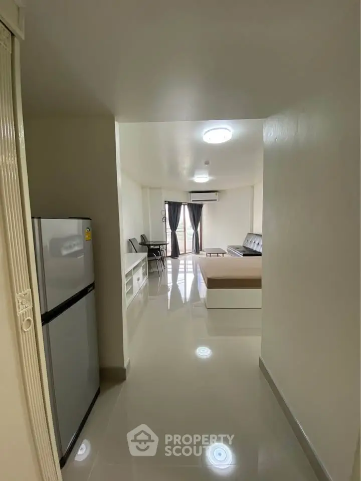 Spacious apartment with modern living room and kitchen area, featuring sleek flooring and natural light.