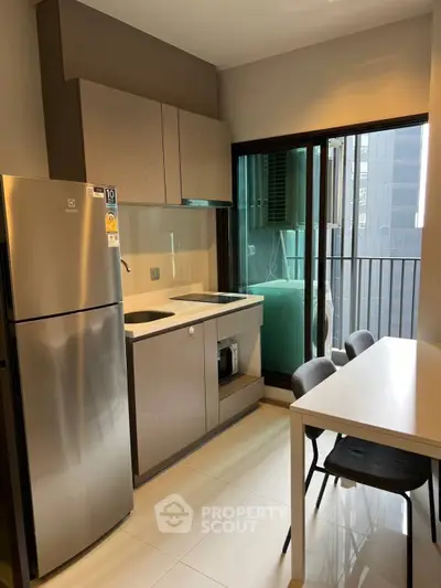 Modern kitchen with sleek appliances and balcony view in urban apartment