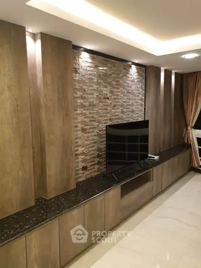 Modern living room with stylish stone accent wall and sleek TV setup.