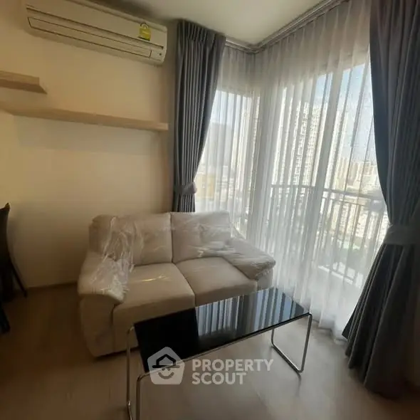 Cozy living room with modern sofa and city view through large windows.