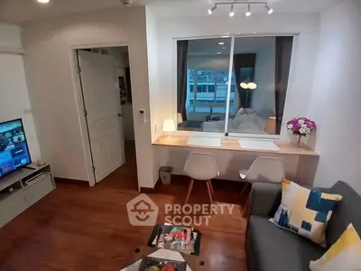 Modern living room with cozy seating and work desk, featuring stylish decor and natural light.