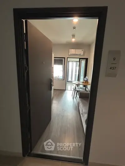 Modern apartment entrance with open door revealing stylish interior and sleek flooring.