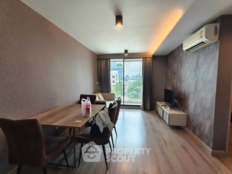 Spacious living room with modern decor and large window offering city views.
